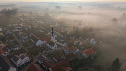 Foggy Bavarian landscape during morning sunrise phase with forest background and small village close which is called P&ouml;rnbach and is located at the region of Pfaffenhofen