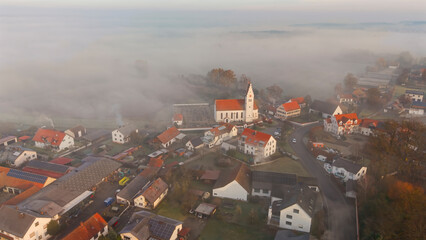 Foggy Bavarian landscape during morning sunrise phase with forest background and small village close which is called P&ouml;rnbach and is located at the region of Pfaffenhofen