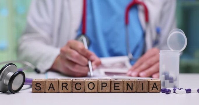 Wooden blocks on medical desk spell word Sarcopenia near medicine capsules. Woman doctor studies patient charts planning therapy for muscle loss