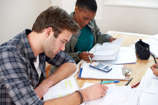 Friends, students and writing notes in university for learning, knowledge or test together. College, team and people on book for information, education or math exam preparation project in classroom - Powered by Adobe