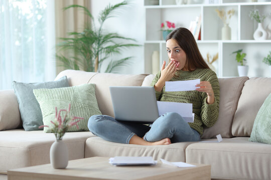 Amazed woman doing online accounting checking laptop