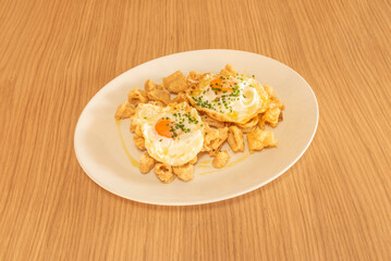 A golden mountain of fried calamari, served in a paper cone on a slate plate, accompanied by brava sauce and homemade aioli