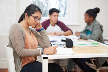Book, girl and student writing at university studying with friends for test, assignment or exam. Reading, education and female person with notes for research with classmates at college campus.