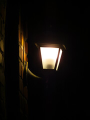 Bright Lantern Illuminates Dark Brick Wall at Night