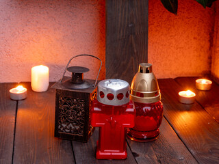 Obraz premium Christian memorial altar with candles, cross, angel figurine, and red grave lamps.