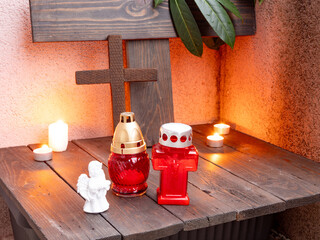 Obraz premium Christian memorial altar with candles, cross, angel figurine, and red grave lamps.