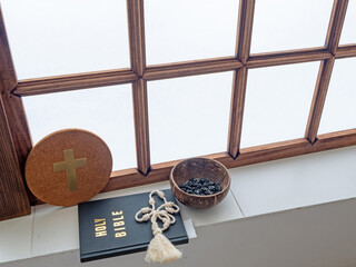 Holy bible and rosary beside near old window in monastery