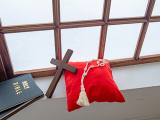 Holy bible and rosary near old window in monastery