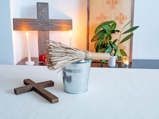 Christian altar with wooden cross, candles and holy water and aspergillum in minimal interior