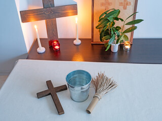 Christian altar with wooden cross, candles and holy water and aspergillum in minimal interior