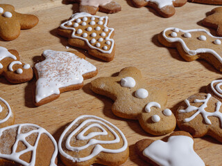 Iced gingerbread cookies in the shape of a man and a tree arranged on a wooden cutting board.