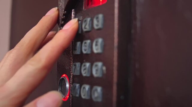 Hand pressing security keypad on metal door panel