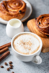 Cappuccino coffee with cinnamon and cinnamon raisin swirl bun, baked puff pastry