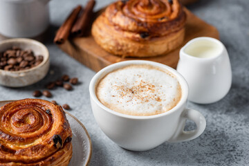 Cappuccino coffee with cinnamon and cinnamon raisin swirl bun, baked puff pastry