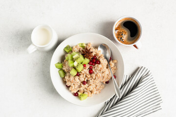 Healthy breakfast oatmeal and spelt porridge with kiwi, cranberries and cup of coffee . Table top...