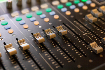 Close-up of an audio mixing console volume control panel.