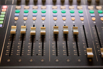 Close-up of an audio mixing console volume control panel.