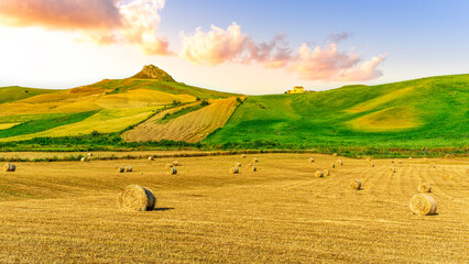 beautiful golden valley with green hills and fields with hay stacks with mountains on background and scenic colorful cloudy sunset on background of landscape © Yaroslav