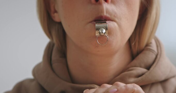 Close Up of Woman Blowing Silver Whistle