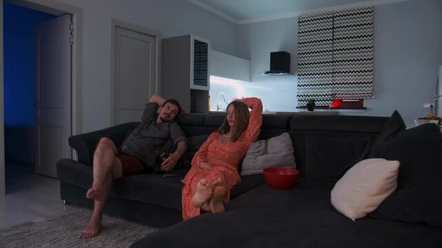 relaxed couple enjoys cozy night watching television with snacks and soft lighting, peaceful and calming evening scene where couple destresses watching tv with popcorn and gentle ambient lighting
