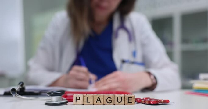 Wooden cubes spell word Plague in front of stethoscope and red tablets. Female doctor fills paperwork in hospital highlighting historical epidemic
