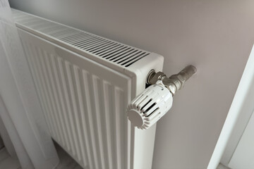 Modern white radiator with a thermostat valve, installed on a wall, providing efficient heating in a contemporary interior space, showcasing home comfort and design