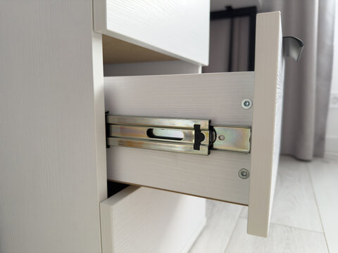 Close-up view of a partially opened white drawer showcasing smooth metal sliding mechanism, highlighting modern furniture design and functionality in a contemporary interior setting