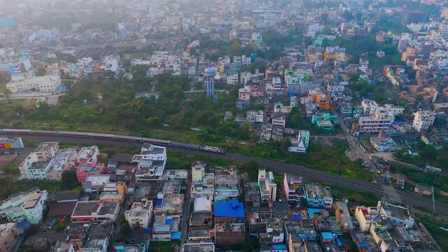 Aerial View of Indian Passenger Train Passing Through Dense Urban Residential Neighborhood at Sunset