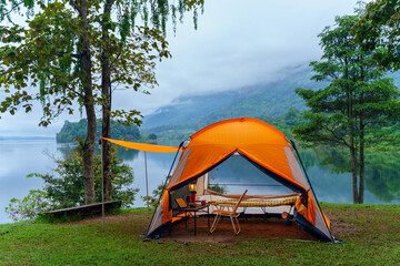 Summer camping adventure in the forest with a tent among green trees and grass