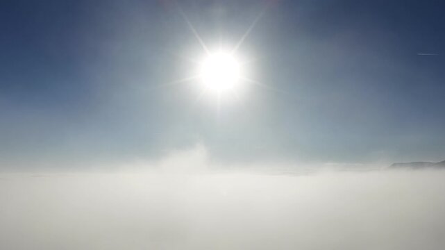 Aerial view of thick clouds under a bright sun, creating a serene, ethereal landscape with contrasting textures and tones, Orschwiller, Grand Est, France.