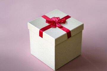Elegant Beige Gift Box with Vibrant Red Bow on Pastel Pink Background, Minimalist Holiday Present