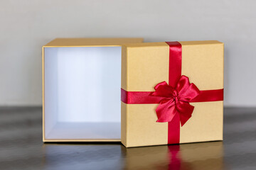 Opened Empty Beige Gift Box with Vibrant Red Ribbon Bow on Dark Table, Ready for Product Mockup