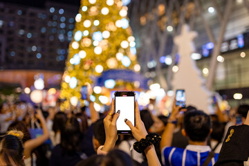 Hands with Ring Holding Phone with White Screen Filming Festive Christmas Tree in City Night Crowd