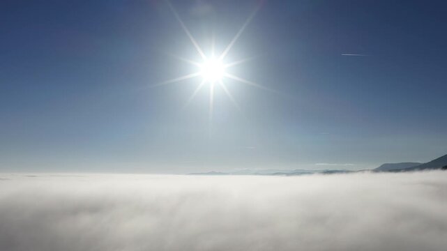 Aerial view of a sea of clouds with mountain peaks poking through, under a bright sun, creating a serene and ethereal landscape, Orschwiller, Grand Est, France.