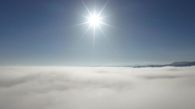 Aerial view of a sea of clouds under a radiant sun, with distant mountains barely visible on the horizon, a dreamy landscape, Orschwiller, Grand Est, France.