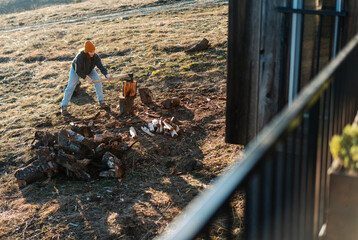 Young woman chopping wood in a country house in the wilderness, winter heating fireplace concept