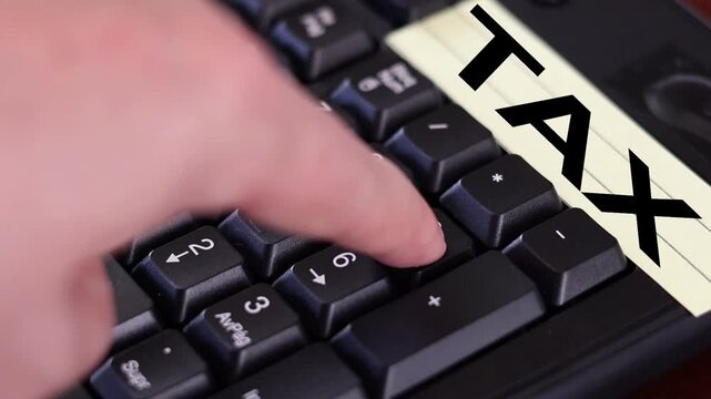 Un primer plano de un teclado con n&uacute;meros con el dedo de una mujer adulta marcando los n&uacute;meros y una nota amarilla con la palabra impuesto