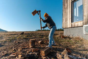 Young woman chopping wood in a country house in the wilderness, winter heating fireplace concept