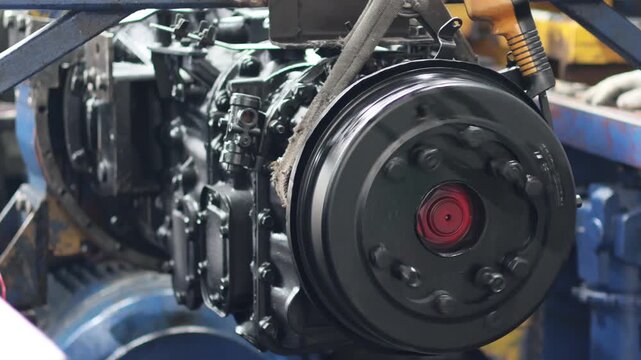 Close up eaton transmission running test on the bench, spinning clutch pulley or flywheel with a central red accent and drive belt.