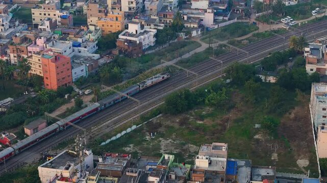 Aerial View of Indian Passenger Train Passing Through Dense Urban Residential Neighborhood at Sunset