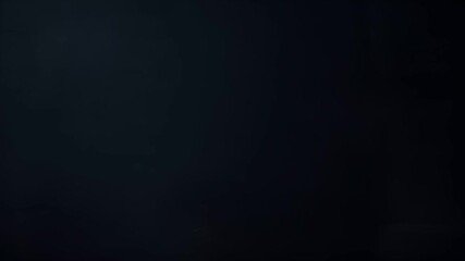 A closeup image of a persons hands holding an orange with leaves. The orange is a vibrant orange with a textured surface, and the leaves are a deep green. The background is dark.