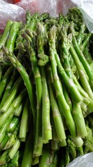Fototapeta premium Fresh green asparagus spears piled together, showing crisp healthy stalks and vibrant natural green hue.