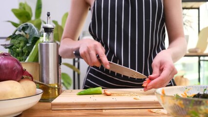 Housewife cleans hot chili pepper and cuts into small pieces on wooden cutting board. Woman removes seeds from spicy pepper on table. Time-lapse