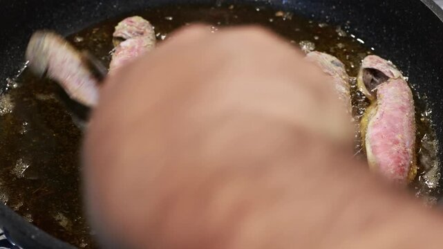 Red mullet are being fried in a pan.