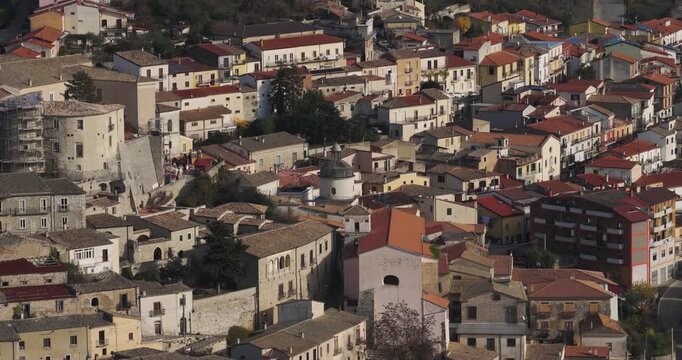 Aerial view of terracotta rooftops and stone buildings cascade down a hillside, creating a rich mosaic of textures and tones, Gesualdo, Irpinia, Italy.