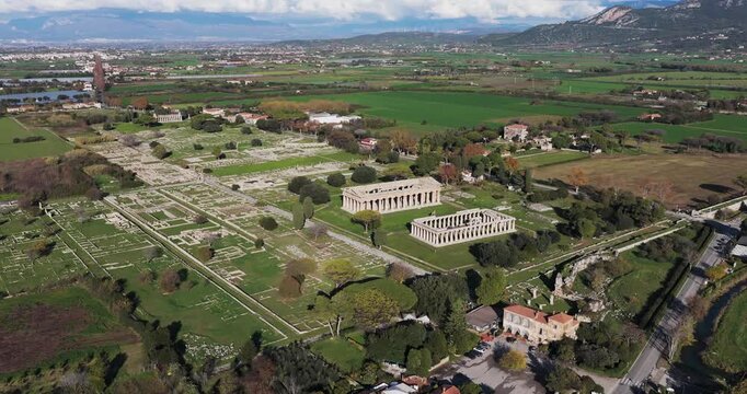 Aerial view of Paestum revealing the Temple of Hera I and Temple of Athena against the backdrop of green fields, Paestum, Campania, Italy.