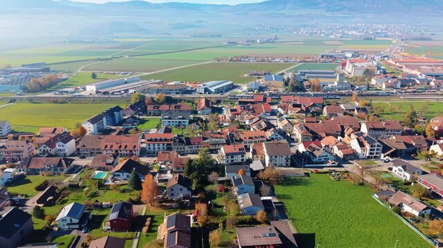 Aerial view of the charming Chavornay cityscape, where buildings nestle amid vivid green fields and distant mountain views, Chavornay, Vaud, Switzerland.
