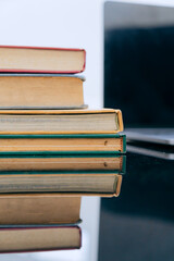 A stack of several books is placed on a table, with the top book left open