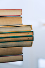 A stack of several books is placed on a table, with the top book left open