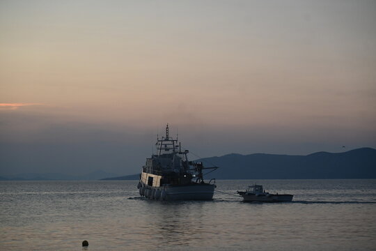 Ship sailing on the calm Aegean sea during sunset near Evia, Greece.